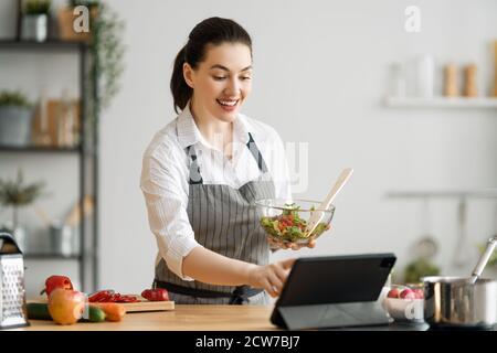 Une alimentation saine à la maison. Une femme heureuse prépare le bon repas dans la cuisine. Banque D'Images