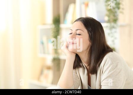 Femme satisfaite relaxant esprit assis sur un canapé dans le salle de séjour à la maison Banque D'Images