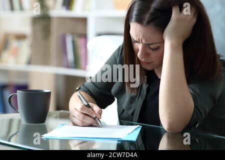 Triste femme qui a signé un document se plaignant assis dans le salon à la maison Banque D'Images