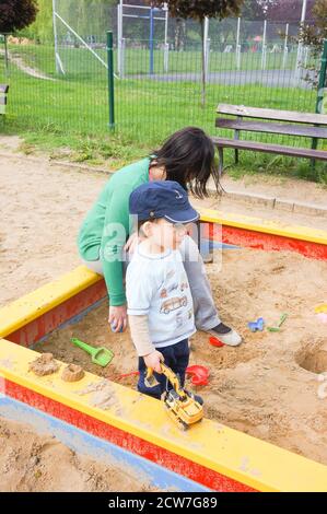 POZNAN, POLOGNE - 14 mai 2016 : une femme et un enfant non identifiés jouant dans une boîte de sable sur un terrain de jeu par temps ensoleillé Banque D'Images