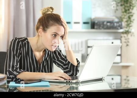 Inquiet femme d'affaires découvrant une erreur en ligne sur un ordinateur portable sur un bureau au bureau Banque D'Images