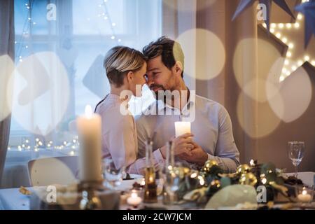 Vue de devant de Happy couple à l'intérieur à la table célébrant Noël. Banque D'Images