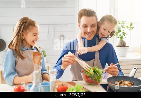 Une alimentation saine à la maison. Bonne famille dans la cuisine. Père et enfants les filles préparent un bon repas. Banque D'Images