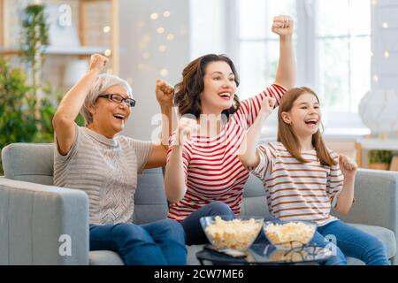 Bonne famille regardant la télévision, films avec pop-corn à la maison. Mère, fille et grand-mère passent du temps ensemble. Banque D'Images