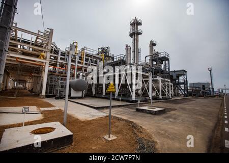 Raffinerie de pétrole et usine de traitement de gaz dans le désert sur le sable jaune. Les tours et les pipelines de Distillin. Signe d'avertissement jaune de dioxyde de soufre (soufre). Banque D'Images