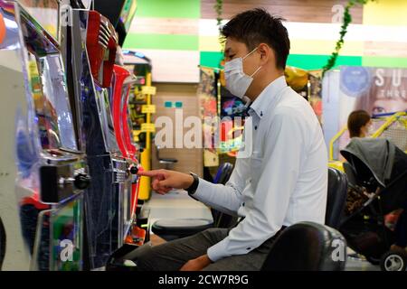 Un homme jouant au jeu de Pachinko tout en portant un masque facial au centre commercial de Ginza dans un contexte de crise du coronavirus (COVID-19).le gouvernement métropolitain de Tokyo a signalé lundi 78 nouveaux cas de coronavirus, en baisse de 66 par rapport à dimanche. Ce nombre est le résultat de 3,003 tests effectués le 25 septembre. Le décompte a porté le total cumulé de Tokyo à 25,335. Le nombre de personnes infectées à Tokyo présentant des symptômes graves est de 26, en baisse de trois par rapport à dimanche, ont indiqué les responsables de la santé. Banque D'Images