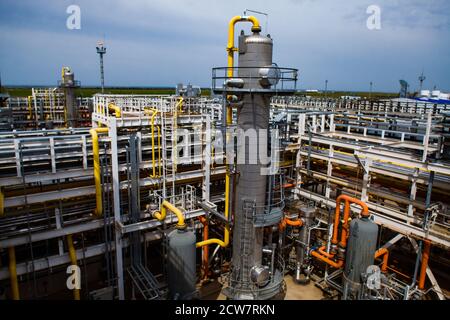 Raffinerie de pétrole et usine de traitement du gaz. Tour de distillation grise (colonne de raffinage). Arrière-plan des pipelines et des tuyaux. Ciel bleu. Banque D'Images