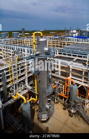 Tour de distillation, canalisations et tuyaux gris. Raffinerie de pétrole et usine de traitement du gaz. Ciel bleu. Effet d'inclinaison partiellement flou. Banque D'Images