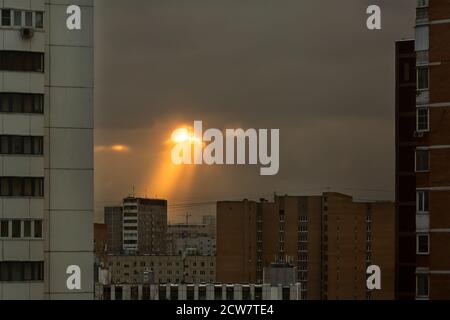 Un phénomène inhabituel dans le ciel au-dessus du quartier résidentiel d'une grande ville. Les rayons du soleil se rendent dans les nuages jusqu'aux immeubles d'une tour dans un quartier résidentiel Banque D'Images