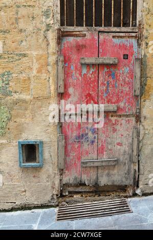 Une porte en bois rouge abîmée est fixée pour empêcher l'entrée dans un vieux bâtiment de la Valette, Malte. Banque D'Images