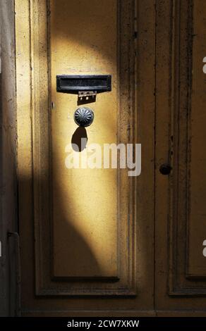 La lumière du soleil illumine un bouton de porte sur la porte jaune d'une résidence à la Valette, Malte. Banque D'Images