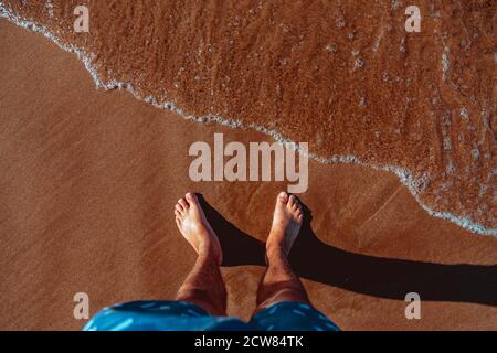 Mans pieds dans l'eau claire on beach Banque D'Images