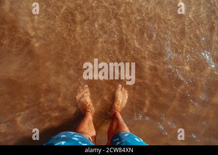 Mans pieds dans l'eau claire on beach Banque D'Images