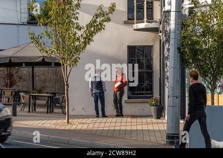 La vie quotidienne. Deux hommes bavardent dans la rue. Greystones. Irlande. Banque D'Images