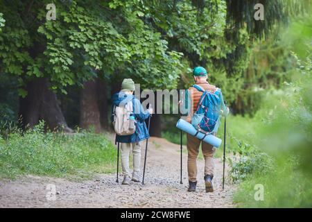 Portrait de père et de fils en pleine longueur à l'arrière, marchant sur un sentier sauvage, portant des sacs à dos et un espace de copie Banque D'Images