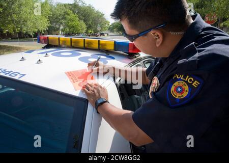 Round Rock, Texas: 20 juillet 2008: Travail de police de routine pendant la journée de travail d'été dans une banlieue nord d'Austin. L'officier Rigo Valles écrit un avertissement sur une voiture garée illégalement. ©Bob Daemmrich Banque D'Images