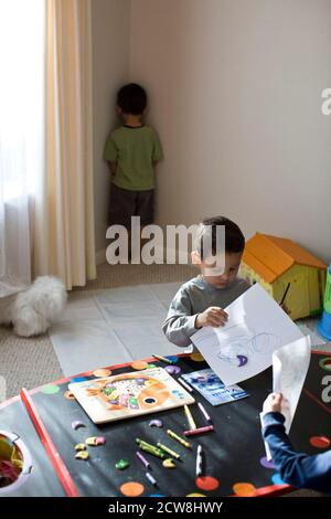 Le garçon hispanique de 4 ans est placé dans le coin « Time Out » pendant que les amis continuent à jouer. ©Bob Daemmrich Banque D'Images