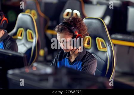 Jouez pour gagner. Jeune fille de race mixte ciblée, gamer professionnel portant des écouteurs jouant des jeux vidéo en ligne, participant à un tournoi eSports. Jeux vidéo en ligne Banque D'Images