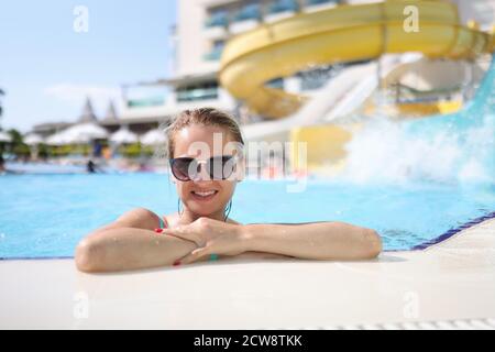 Femme dans des lunettes de soleil près du côté au parc aquatique. Banque D'Images