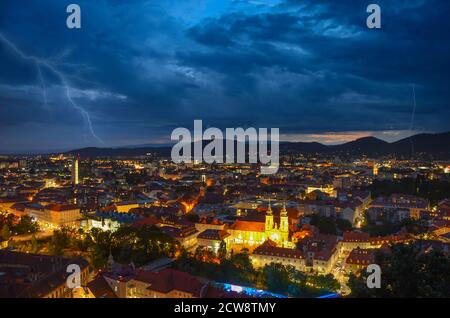 Tempête de foudre avec des nuages dramatiques sur la ville de Graz, avec l'église Mariahilfer et des bâtiments historiques, dans la région de Styrie, en Autriche Banque D'Images