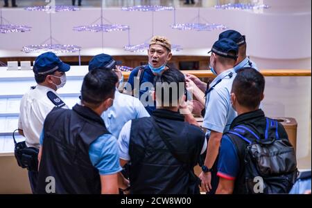 Des policiers portant un masque vérifient l'identité d'un manifestant pendant la manifestation pour commémorer le 6e anniversaire du mouvement Umbrella.des dizaines de manifestants pro-démocratie se sont rassemblés dans le centre commercial Pacific place à Hong Kong pour marquer le 6e anniversaire du mouvement Umbrella où Hong Kongers ont pris dans la rue et occupé le les routes principales de la ville pour exiger le suffrage universel. Banque D'Images