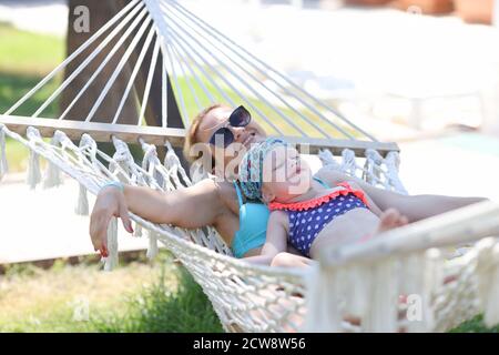 Une femme avec une fille se trouve dans un hamac dans la nature avec des yeux fermés. Banque D'Images