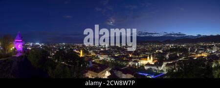 Lumières de la ville de Graz et la célèbre tour de l'horloge (Grazer Uhrturm) sur la colline de Shlossberg, Graz, région de Styrie, Autriche, après le coucher du soleil. Vue panoramique. Banque D'Images