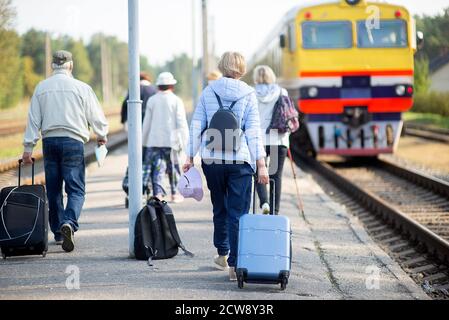 vue arrière d'un groupe de personnes âgées âgées âgées qui attendent pour un train à voyager Banque D'Images
