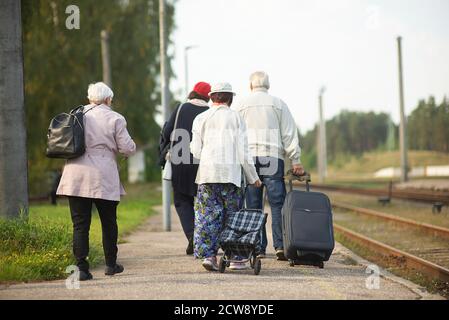 vue arrière d'un groupe de personnes âgées âgées âgées vieux avec bagages en attente d'un train pour voyager Banque D'Images