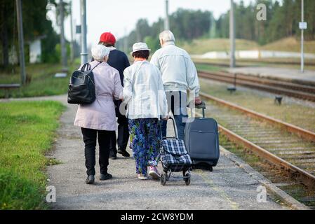 vue arrière d'un groupe de personnes âgées âgées âgées vieux avec bagages en attente d'un train pour voyager Banque D'Images