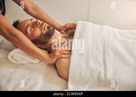 Masseur professionnel massant les épaules des clients masculins au salon de spa Banque D'Images