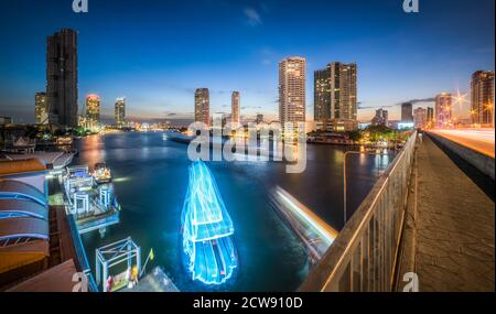 Gratte-ciels et sentiers de circulation sur la rivière Chao Phraya à Bangkok, en Thaïlande, vu depuis le pont Taksin au crépuscule Banque D'Images