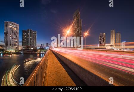 Gratte-ciels et feux de circulation sur le pont Taksin traversant la rivière Chao Phraya à Bangkok, Thaïlande au crépuscule Banque D'Images