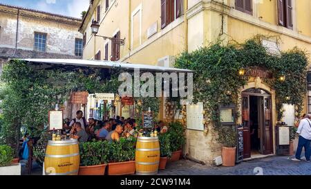 Les touristes apprécient le déjeuner dans un pittoresque café italien-terrasse couvert de lierre dans le quartier Trastevere de la ville historique de Rome, en Italie Banque D'Images