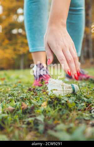 Une femme prend un shuttlecock de badminton de l'herbe. Gros plan de la main. Mode de vie actif. Banque D'Images