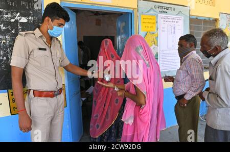 Beawar, Rajasthan, Inde, 28 septembre 2020 : les électeurs se désinfectent les mains en attendant de voter pour les élections Panchayati Raj, dans le contexte de la pandémie du coronavirus, au village de Jala ki Chauki près de Beawar. Plus de 83.50 pour cent des électeurs de 31.95-lakh ont voté dans la première phase des 947 grammes panchayat (conseil de village) des élections dans 25 districts de l'État. Les lignes directrices relatives à la COVID-19 n'ont pas été suivies pendant l'élection. Les électeurs portent un masque facial, mais n'ont pas maintenu de distanciation sociale. Crédit : Sumit Saraswat/Alay Live News Banque D'Images