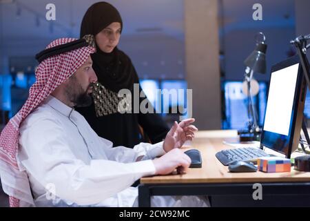 Un homme d'affaires arabe handicapé dans la tradition s'adapte avec une femme arabe assiposante travaillant au bureau. Homme d'affaires handicapés dans le fauteuil roulant travaille dans l'o Banque D'Images