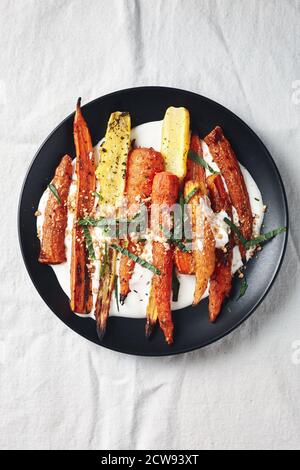 Salade de carottes rôties avec yaourt, épices et herbes. Banque D'Images