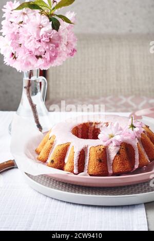 Gâteau Bundt festif aux couleurs roses, orné de fleurs de cerisier. Banque D'Images