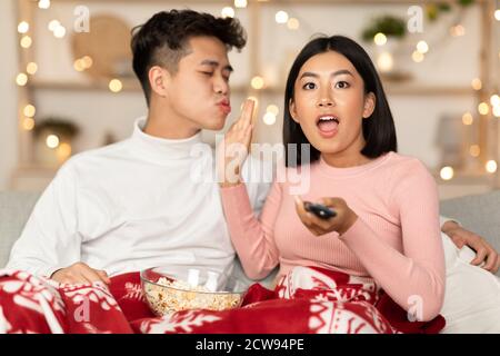 Une femme asiatique excitée regardant la télévision refusant à Kiss mari à l'intérieur Banque D'Images