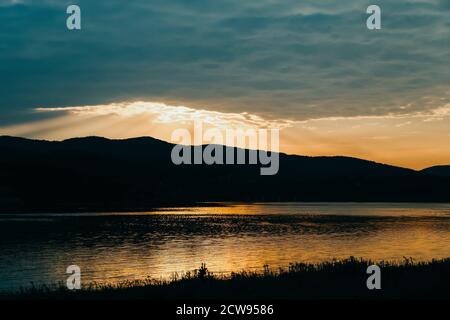 Magnifique coucher de soleil doré dans l'eau du lac. Lac Mucharz. Jezioro Mucharskie, Pologne Banque D'Images