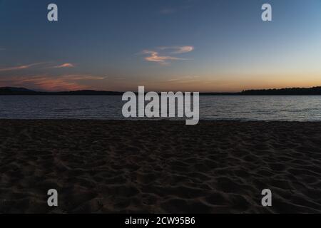 Le coucher de soleil sur un lac depuis une plage à Lake Placid, NY Banque D'Images