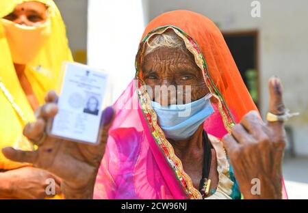 Beawar, Rajasthan, Inde, 28 septembre 2020 : une femme âgée votant Bardi Devi montre son identité d'électeur et son doigt à la main après avoir voté avec sa belle-fille lors des élections de Panchayati Raj, dans le contexte de la pandémie de coronavirus en cours, au village de Sendra près de Beawar. Plus de 83.50 pour cent des électeurs de 31.95-lakh ont voté dans la première phase des 947 grammes panchayat (conseil de village) des élections dans 25 districts de l'État. Les lignes directrices relatives à la COVID-19 n'ont pas été suivies pendant l'élection. Les électeurs portent un masque facial, mais n'ont pas maintenu de distanciation sociale. Crédit : Sumit Saraswat/Alay Live News Banque D'Images