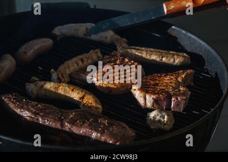 Gros plan sur les steaks et les saucisses cuits à l'extérieur gril Banque D'Images