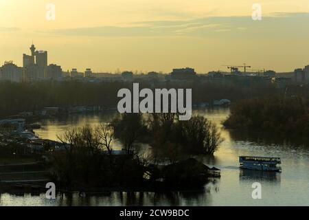 Un bateau traverse la confluence des rivières au coucher du soleil à Belgrade Banque D'Images