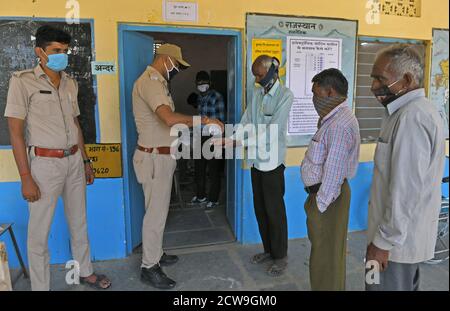 Les électeurs se désinfectent les mains alors qu'ils attendent de voter pour les élections Panchayati Raj, dans le contexte de la pandémie de coronavirus, au village de Jala ki Chauki près de Beawar. Plus de 83.50 pour cent des électeurs de 31.95-lakh ont voté dans la première phase des 947 grammes panchayat (conseil de village) des élections dans 25 districts de l'État. Les lignes directrices relatives à la COVID-19 n'ont pas été suivies pendant l'élection. Les électeurs portent un masque facial, mais n'ont pas maintenu de distanciation sociale. (Photo de Sumit Saraswat/Pacific Press) Banque D'Images