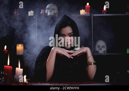 Portrait de l'asiatique mystère fortune teller en robe noire avec fond de fumée. Banque D'Images