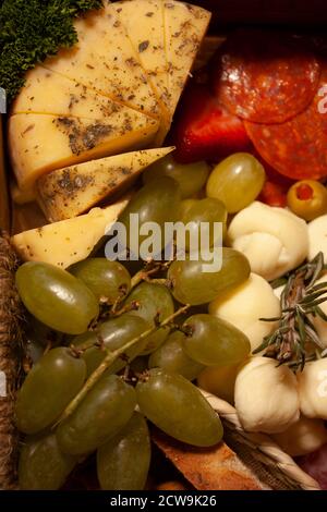 Délicieux plat gastronomique au fromage garni de morceaux de basilic et de persil séchés accompagnés de raisins, de fromage blanc et de pain Banque D'Images