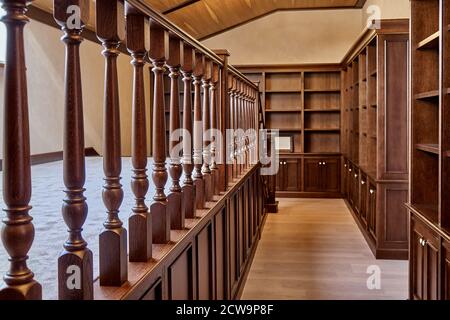 Bibliothèque personnelle. Bibliothèque en bois avec des étagères vides et une balustrade en bois placée dans la maison bibliothèque dans la maison Banque D'Images