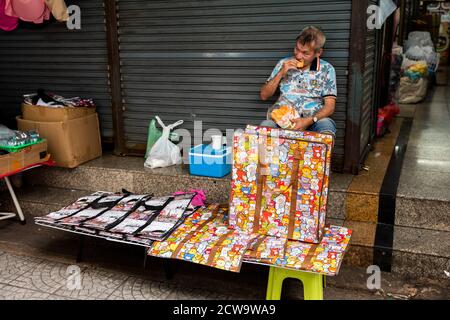 Un homme qui a son déjeuner apparaît dans un autre monde sur son site de vente dans le quartier chinois de Bangkok. Banque D'Images